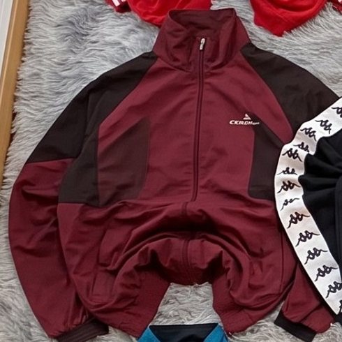 Chaqueta de chándal Chaqueta granate extendida sobre una alfombra gris