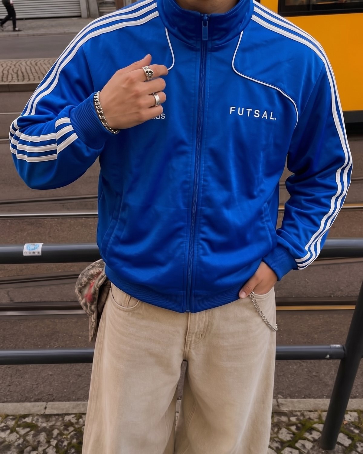 Chaqueta Adidas Futsal azul de tres rayas puesta con vaqueros anchos beis