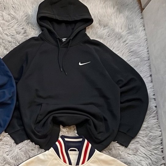 Sudadera con capucha Nike negra extendida sobre una alfombra gris
