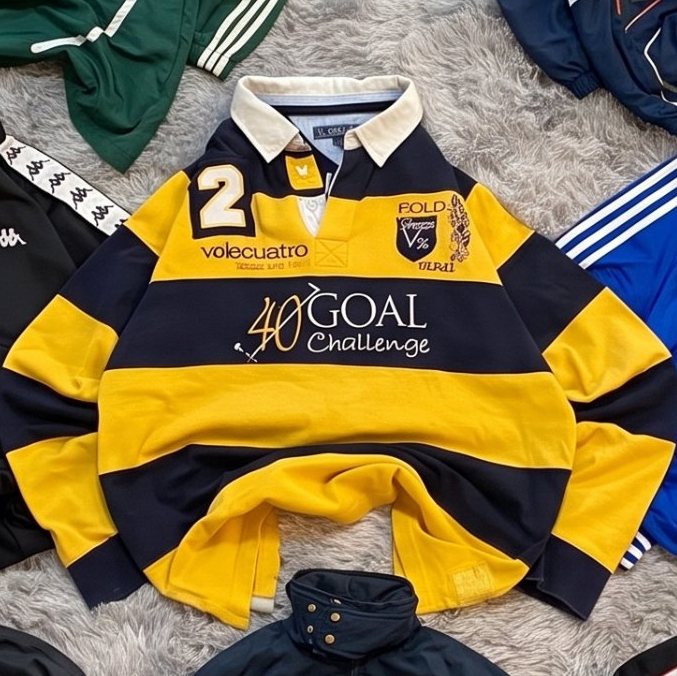 Polo de rugby a rayas Rugby amarillo y marino extendida sobre una alfombra gris
